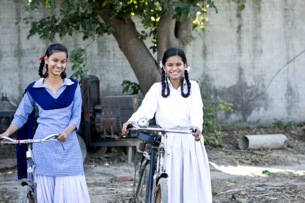 Indian girls in school uniform standing with bicycles