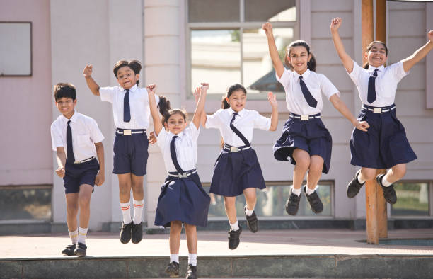 Schoolboys and schoolgirls jumping and celebrating in school campus