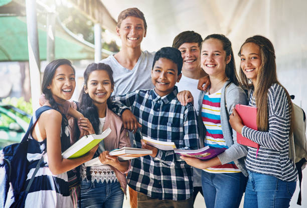 Portrait of a group of happy schoolchildren standing together in the hall outside their classroom